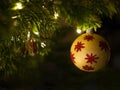 Golden decorative ball with red shiny ornaments hanging on christmas tree