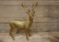 Golden deer in front of a wooden wall. Christmas decoration Royalty Free Stock Photo