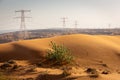 Golden desert dunes landscape with transmission towers on the horizon, Dubai, UAE.