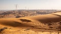 Golden desert dunes landscape with transmission towers on the horizon, UAE.