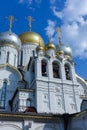 Golden domes with crosses of an orthodox temple on the background of bright blue sky. Snow-white facade. Christian faith