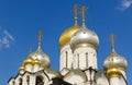 Golden domes with crosses of an orthodox temple on the background of bright blue sky. Snow-white facade. Christian faith