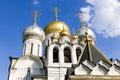 Golden domes with crosses of an orthodox temple on the background of bright blue sky. Snow-white facade. Christian faith