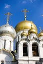 Golden domes with crosses of an orthodox temple on the background of bright blue sky. Snow-white facade. Christian faith