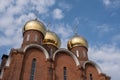 Golden domes with crosses of a red stone church on a background of blue sky with clouds Royalty Free Stock Photo