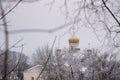 The Golden domes of the white Church against the overcast sky are photographed through the branches of trees Royalty Free Stock Photo