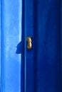 Golden doorknocker with hand shape on blue wooden door