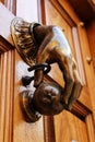 Golden doorknocker with hand shape on old wooden door