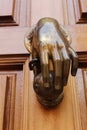 Golden doorknocker with hand shape on old wooden door