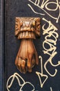 Golden doorknocker with hand shape on old wooden door