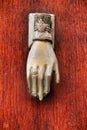 Golden doorknocker with hand shape on old wooden door Royalty Free Stock Photo