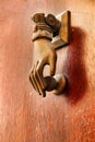 Golden doorknocker with hand shape on old wooden door