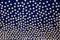 Golden dots on a dark background. Dark blue background with polka dots, fabric texture with a pattern.