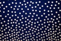 Golden dots on a dark background. Dark blue background with polka dots, fabric texture with a pattern.