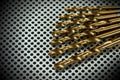 Golden Drill Bits on a Metal Background with Many Holes