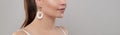 Golden earring on ear of beautiful model on grey banner background
