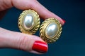 golden earrings with red nail polish on a dark blue background Royalty Free Stock Photo