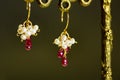 Golden earrings with red rubies with white pearls on black background. Royalty Free Stock Photo