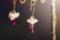 Golden earrings with red rubies with white pearls on black background. Royalty Free Stock Photo