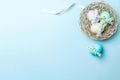 Golden easter colour eggs in basket with spring tulips, white feathers on pastel blue background in Happy Easter decoration. Royalty Free Stock Photo