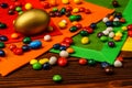 Golden Easter egg with sweets and multicolored napkins on wooden background