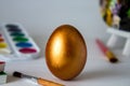 Golden Easter egg on a watercolor background. Simple holiday composition. Art work, handmade for decoration for Easter