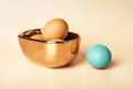 Golden Easter eggs in bowl and outstanding blue dyed one on beige background. Preparation for spring holiday celebration
