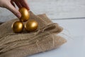 Golden easter eggs on white rustic background. Hand holding an egg Royalty Free Stock Photo