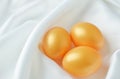 Golden easter eggs on white satin textile background Royalty Free Stock Photo