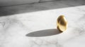 golden egg on marble surface, casting soft shadow in natural light Royalty Free Stock Photo