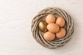 Golden egg among others in nest on wooden background, top view Royalty Free Stock Photo