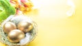 Golden eggs in basket with spring tulips, white feathers on pastel yellow background in Happy Easter decoration. Foil minimalist Royalty Free Stock Photo