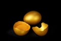 Golden eggs and half broken egg with yolk isolated at black background Royalty Free Stock Photo