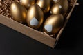 Golden eggs in paper box on dark table