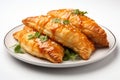 Golden empanadas, stuffed with savory fillings, on a clean white background