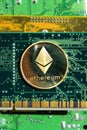 Golden Ethereum coin lying on computer motherboard, cryptocurrency investing, blockchain technology