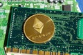 Golden ethereum coin lying on computer motherboard, cryptocurrency investing concept
