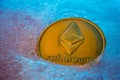 Golden Ethereum coin, online digital currency frozen in the blue ice. Concept of block chain, market crash. Frozen crypto money,