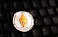 Golden Ethereum ETH coin over black keyboard