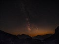 Golden evening light gently illuminates the mountains under the starry sky. Royalty Free Stock Photo