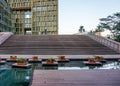 A golden exterior of a modern building with a pond and flowers outdoor.