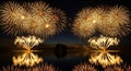 Golden fireworks exploding over lake at night. Festive pyrotechnic display with reflection in water for celebration New Year Royalty Free Stock Photo