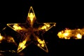 A golden five-pointed star, shining against the background of bokeh and blurred lights of garlands. Royalty Free Stock Photo