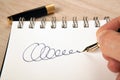 Golden fountain pen in the hand and a signature on the paper Royalty Free Stock Photo