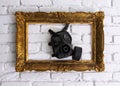 Golden frame with black gas mask on white brick wall Royalty Free Stock Photo