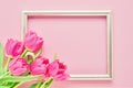 Golden frame with pink tulips on pink background. Mockup. Top view, copy space Royalty Free Stock Photo