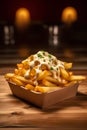 Golden French fries with mayonnaise in a cardboard box on a wooden table