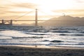 Golden Gate Bridge at dusk with a gpld brown pastel sky and an outline of a kite surfer