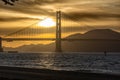 Golden Gate Bridge at dusk with a gpld brown pastel sky and an outline of a kite surfer