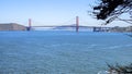 The Golden Gate Bridge at Mile Rock Beach with blue ocean water, waves, rocks and lush green trees on Lands End Trail Royalty Free Stock Photo